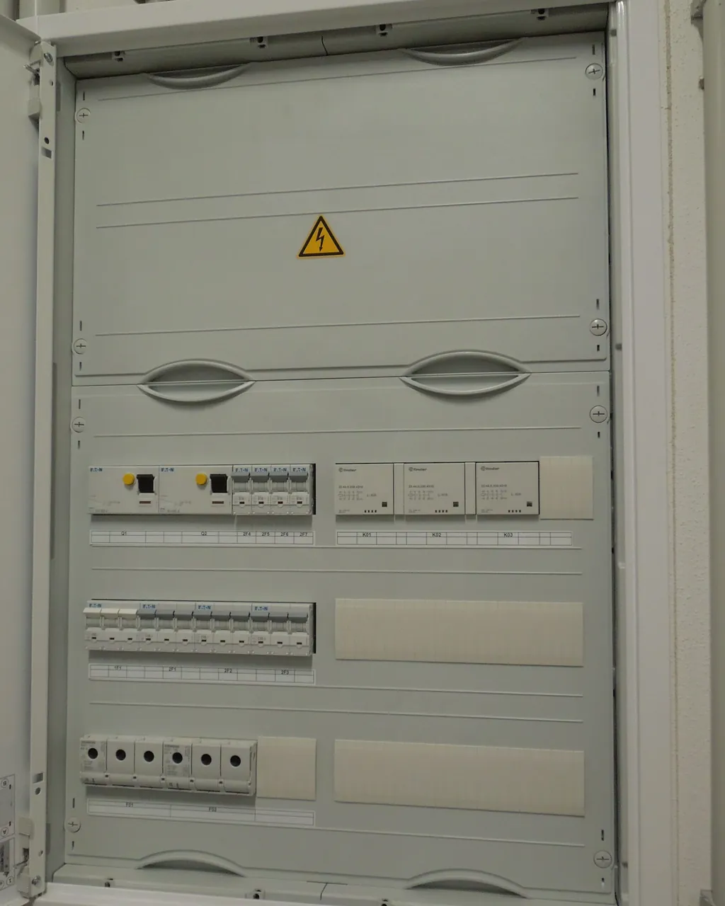 Geöffnete Unterverteilung einer ortsfesten elektrischen Anlage mit Fehlerstrom- und Leitungsschutzschaltern, Installationsrelais und beschrifteten Stromkreisen
